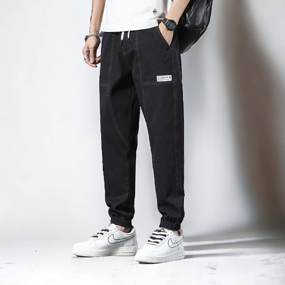 Men's Vinny Denim Joggers in black, relaxed fit, paired with casual sneakers.