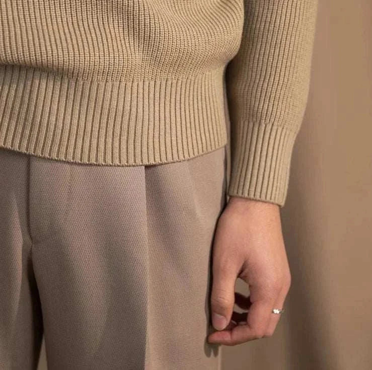 Autumn warm wool sweater in beige, featuring ribbed cuffs and hem, paired with neutral trousers.