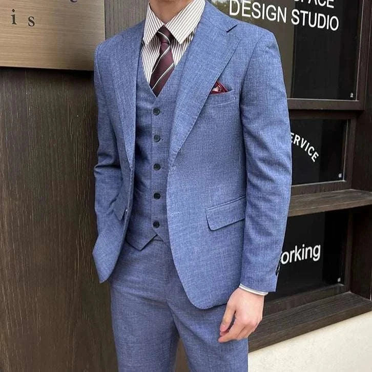 Groom in stylish blue 3 piece wedding suit with tie and pocket square.