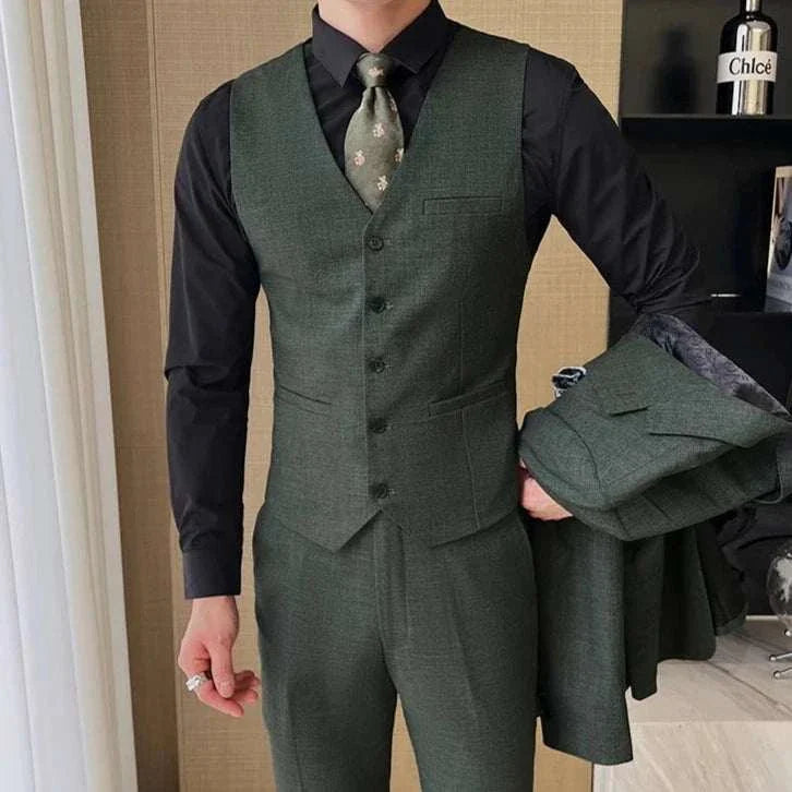 Groom wedding 3 piece suit in dark green, featuring a waistcoat, jacket, and trousers, paired with a black shirt and floral tie.