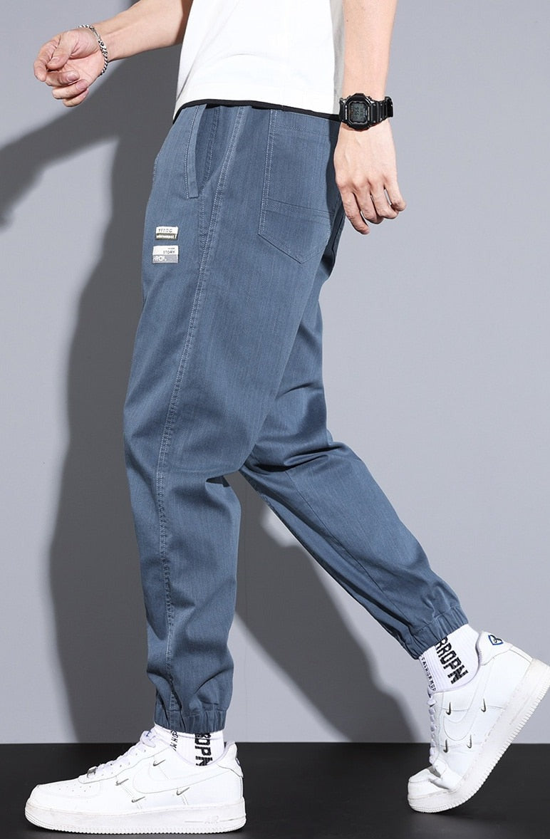 Vinny Loose Pants in blue, men's relaxed fit jogging pants with pockets, paired with casual white sneakers.