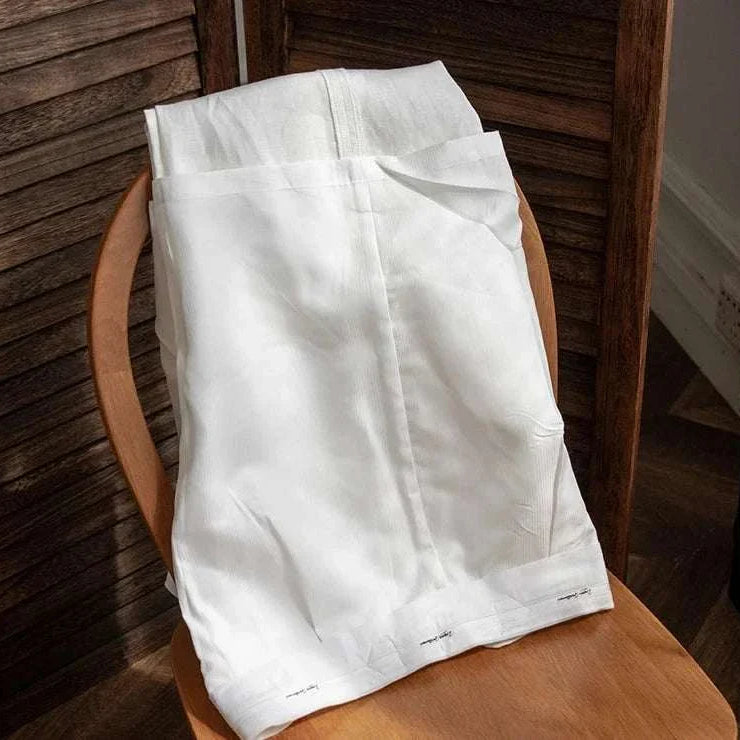 Lightweight Italian high-waist linen trousers on a wooden chair.