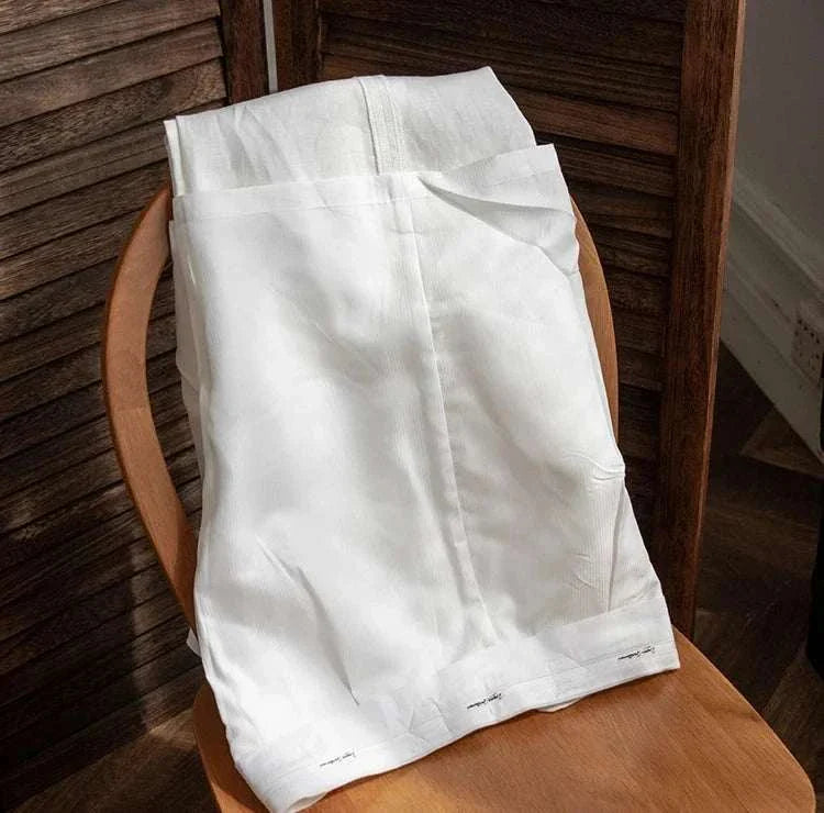 Lightweight Italian high-waist linen trousers on a wooden chair.