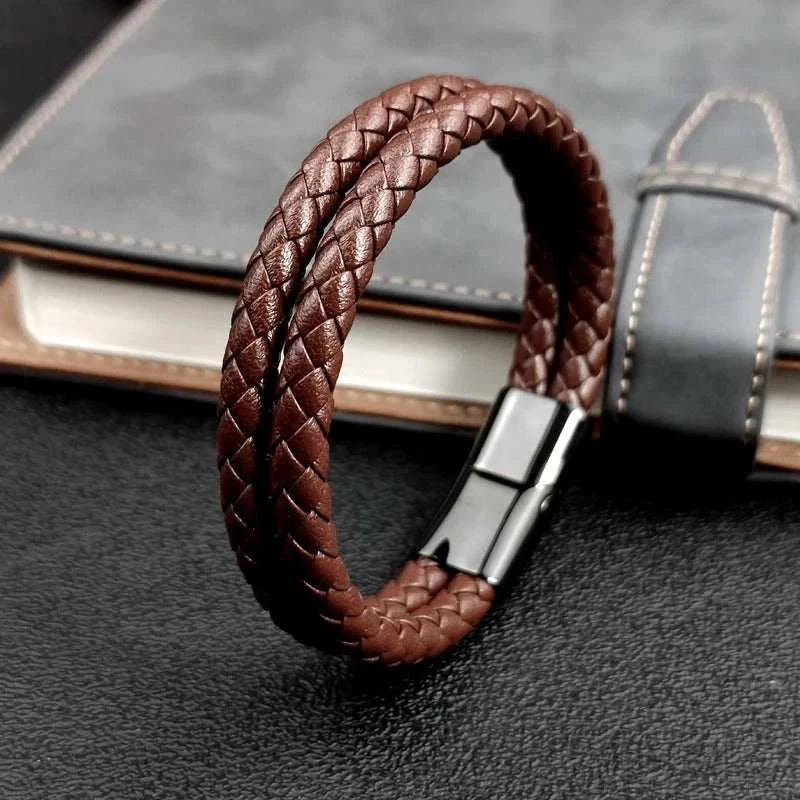 Double band leather bracelet with stainless steel clasp on a notebook background.