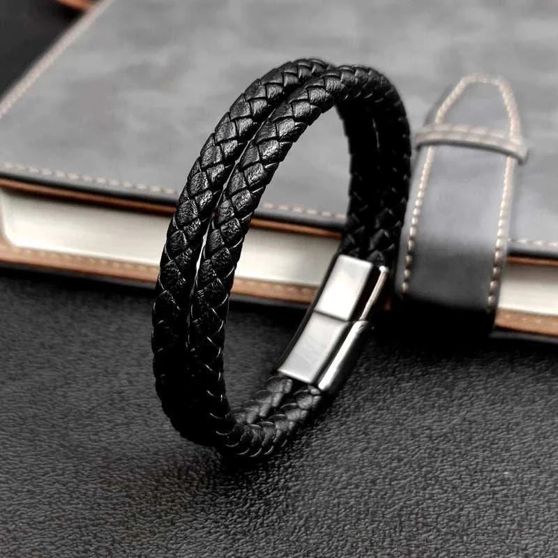 Double band leather bracelet with stainless steel clasp on a textured surface.