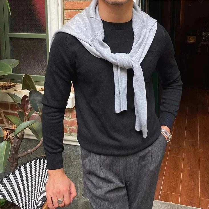 Stylish man wearing Antonios office premium sweater in black, accessorized with a light gray sweater draped over shoulders, perfect for work or business travel.