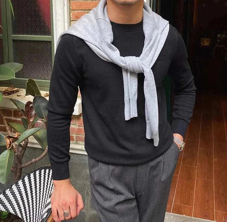 Stylish man wearing Antonios office premium sweater in black, accessorized with a light gray sweater draped over shoulders, perfect for work or business travel.