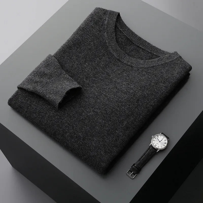 Antonios Pure Wool Sweater in dark grey, folded on a table, accompanied by a watch.