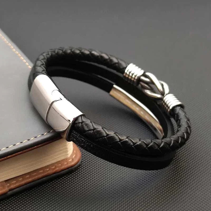 Triple layer leather bracelet with stainless steel accents on a black surface.