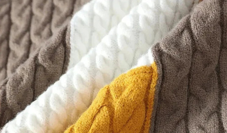 Cable-knit fabric detail of Norway neck sweater in brown, white, and yellow.