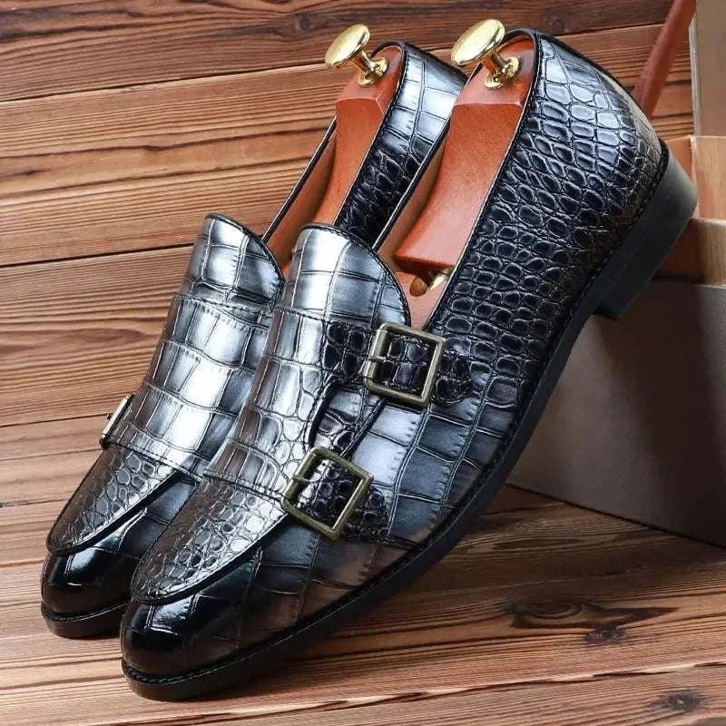 Crocodile pattern microfiber shoes for men in black and silver with buckle detail on wooden background.