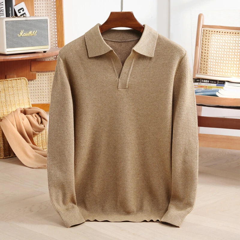 Beige sweater on a hanger with a blurred indoor background