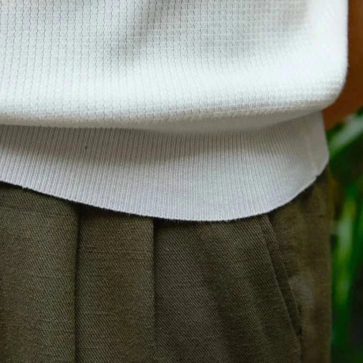 Close-up of a white summer v-neck polo t-shirt paired with dark pants.