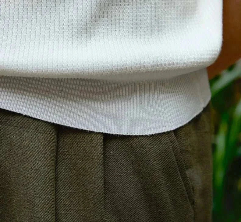 Close-up of a white summer v-neck polo t-shirt paired with dark pants.