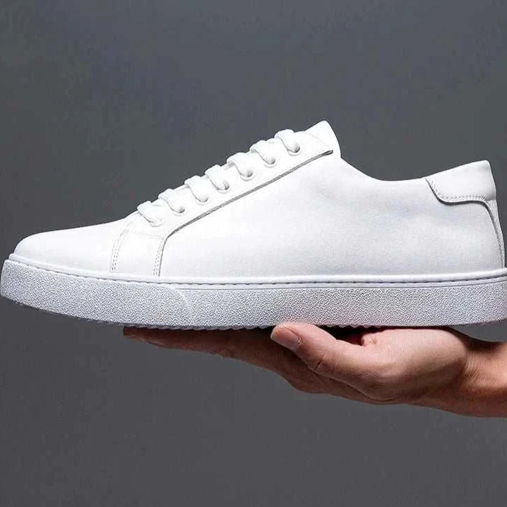 White LUXELY office leather shoe held in hand, showcasing sleek design and comfort for men.