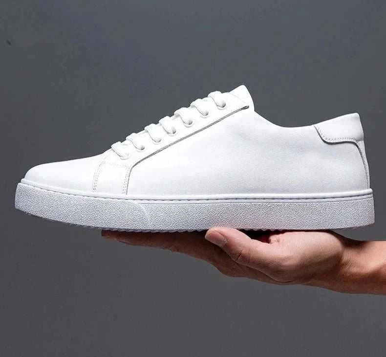 White LUXELY office leather shoe held in hand, showcasing sleek design and comfort for men.