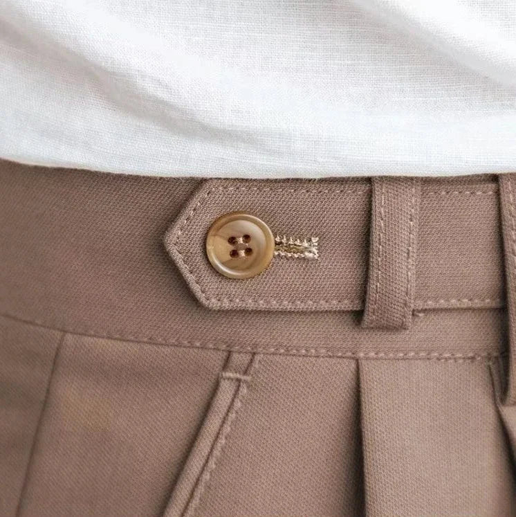 Antonios draped suit pants close-up showcasing button detail and fabric texture.