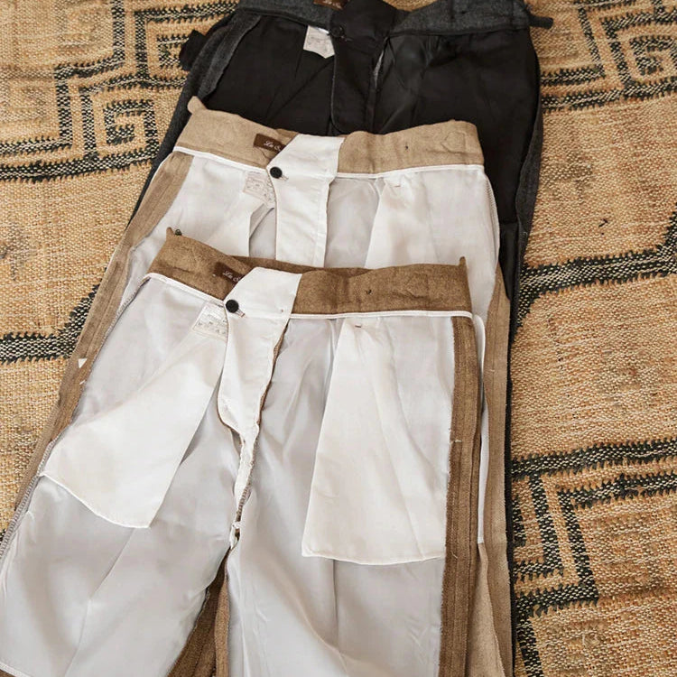 Wool winter Italian trousers in various colors laid out on a textured surface.