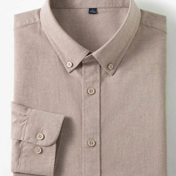 A folded long-sleeve button-up shirt in a light taupe-beige color, displayed on a clean white background with two small inset detail images on the right showing a cotton graphic and fabric texture.