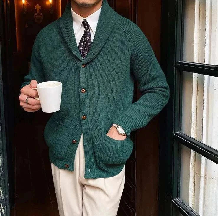 Man wearing Oxford premium cardigan in dark green, holding a white mug.