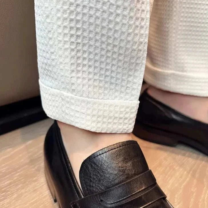 Close-up of suit formal office pants in textured fabric, paired with black leather shoes.