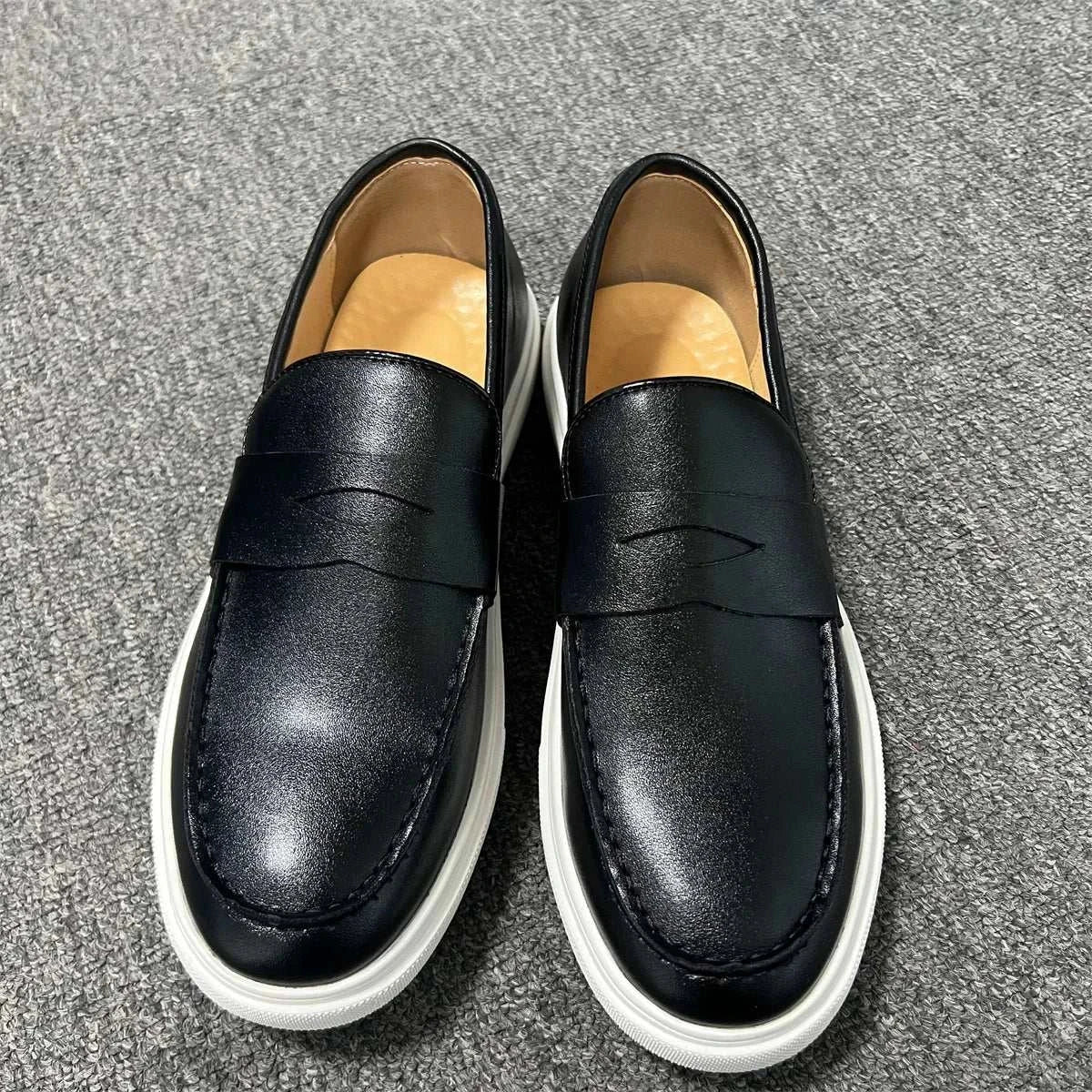 Casual slip loafers in black with cushioned insoles on gray carpet background.