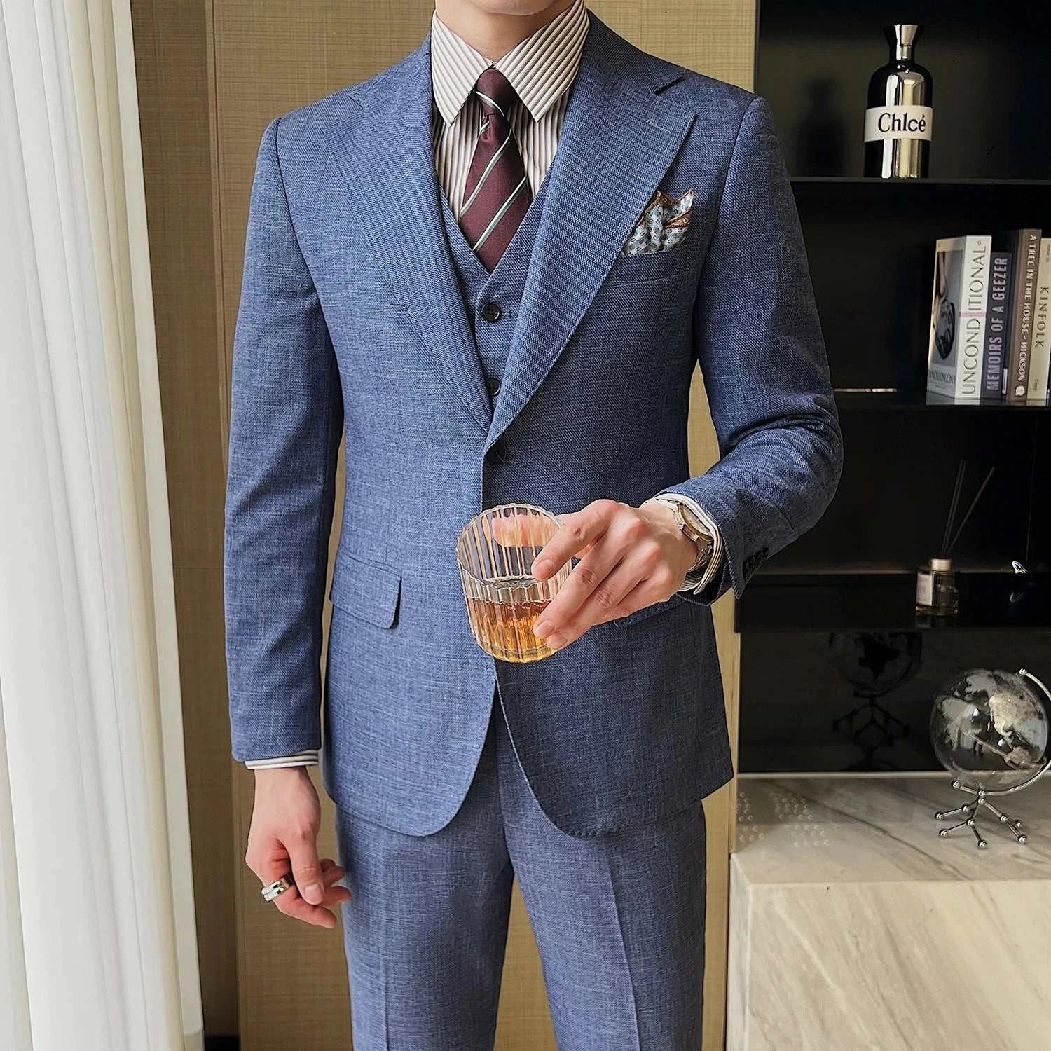 Groom in blue wedding 3 piece suit holding a glass, stylish and elegant attire.