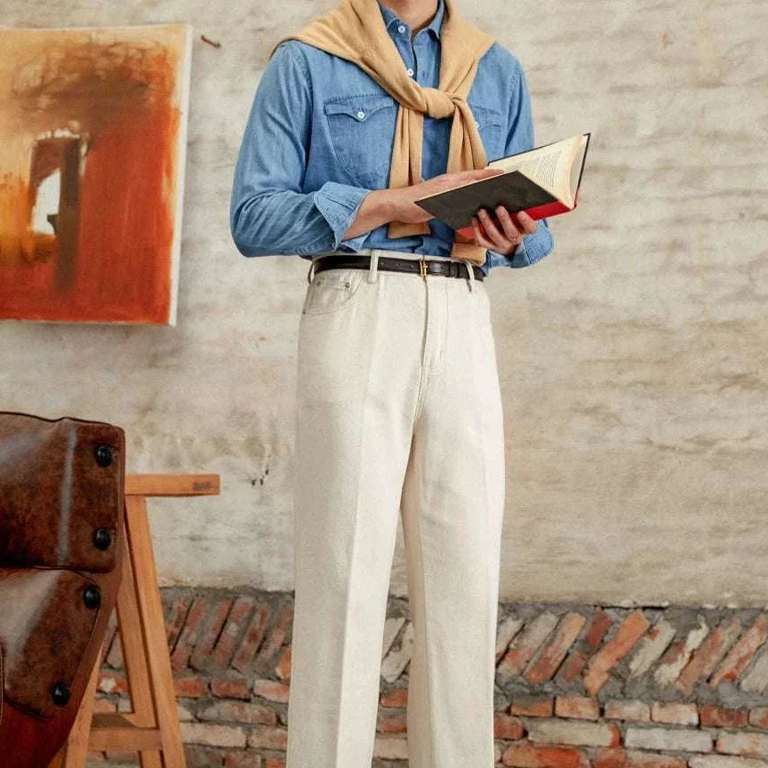 British pure cotton old money pants on a man reading a book, styled with a denim shirt and sweater.