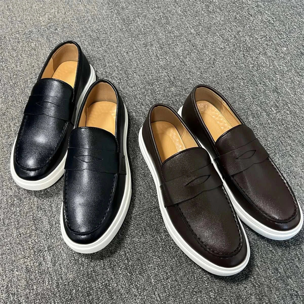 Casual slip loafers for men in black and brown with white soles on gray carpet.
