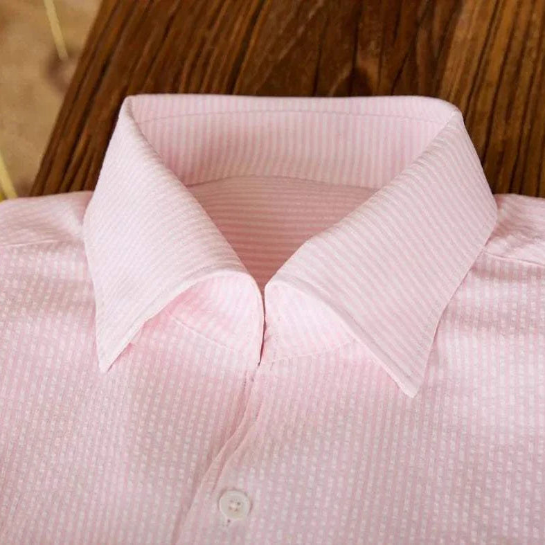 Vintage Italian long sleeve shirt in soft pink cotton fabric on wooden surface.