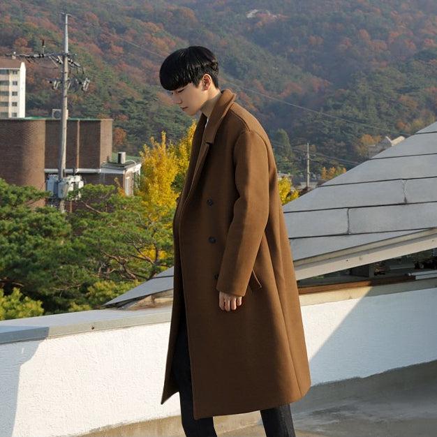 Man wearing a woolen Korean long coat outdoors in a fall setting.