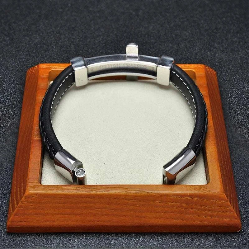 Cross stainless steel leather bracelet with sleek design on display stand.