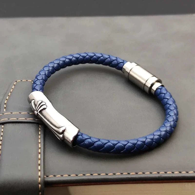 Leather bracelet with stainless steel cross on a leather surface.