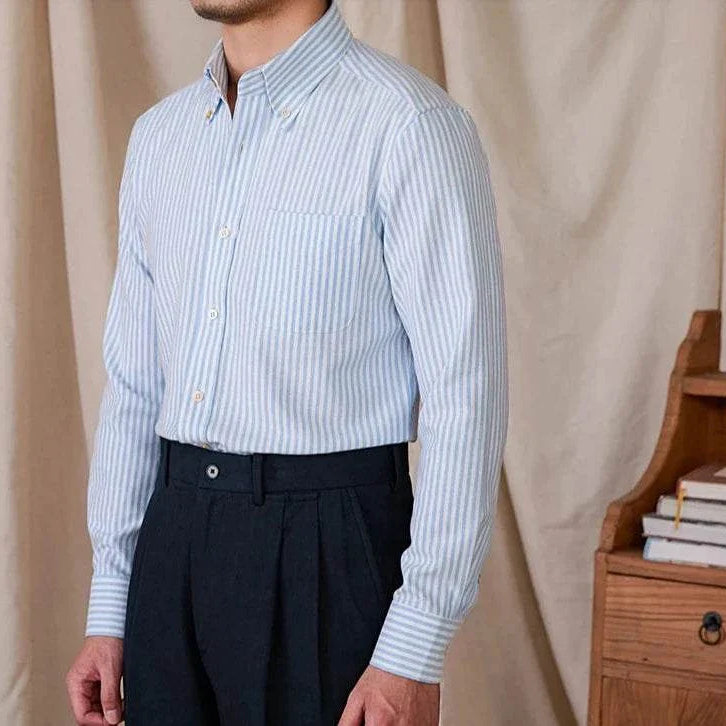 Oxford style casual cotton shirt for men in blue with vertical stripes, buttoned collar, and long sleeves.