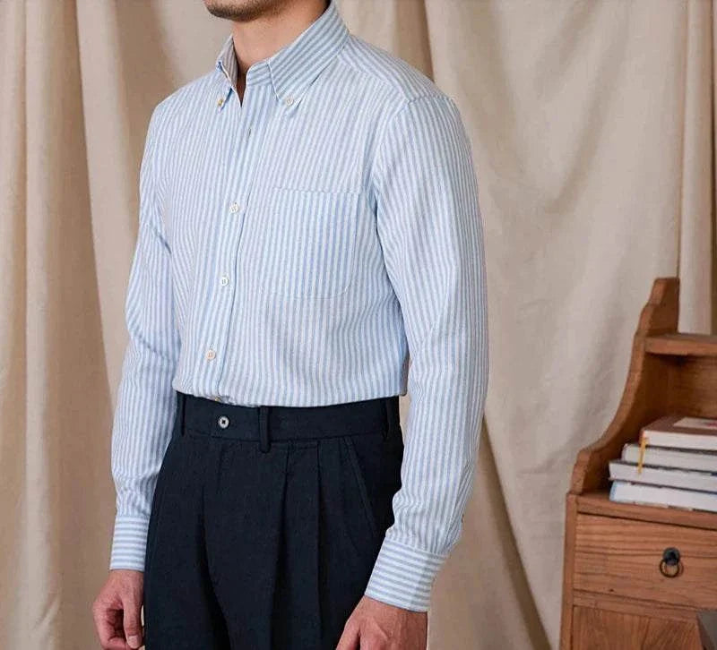Oxford style casual cotton shirt for men in blue with vertical stripes, buttoned collar, and long sleeves.