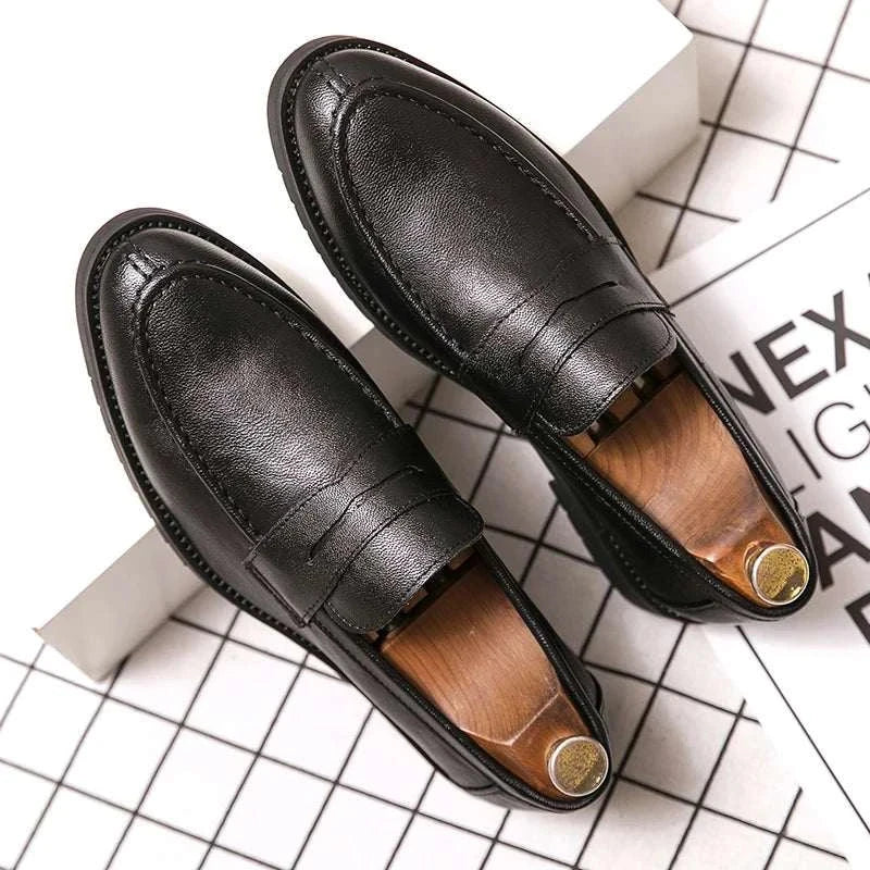 Black British casual loafers on a grid background.