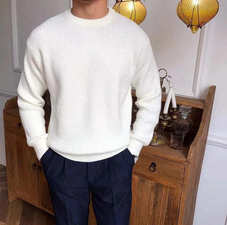 Antonios solid round neck knit sweater in white worn by a male model in a cozy setting.