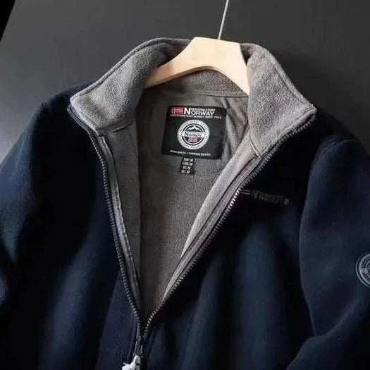 Norway puffer jacket in navy, lightweight and warm, hanging on a wooden hanger.