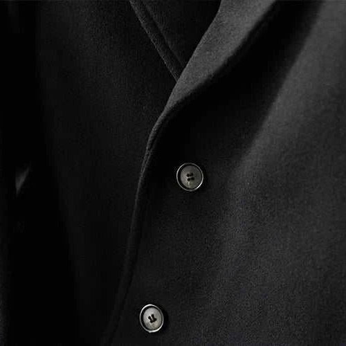 Close-up of a black single breasted trench coat with buttons.