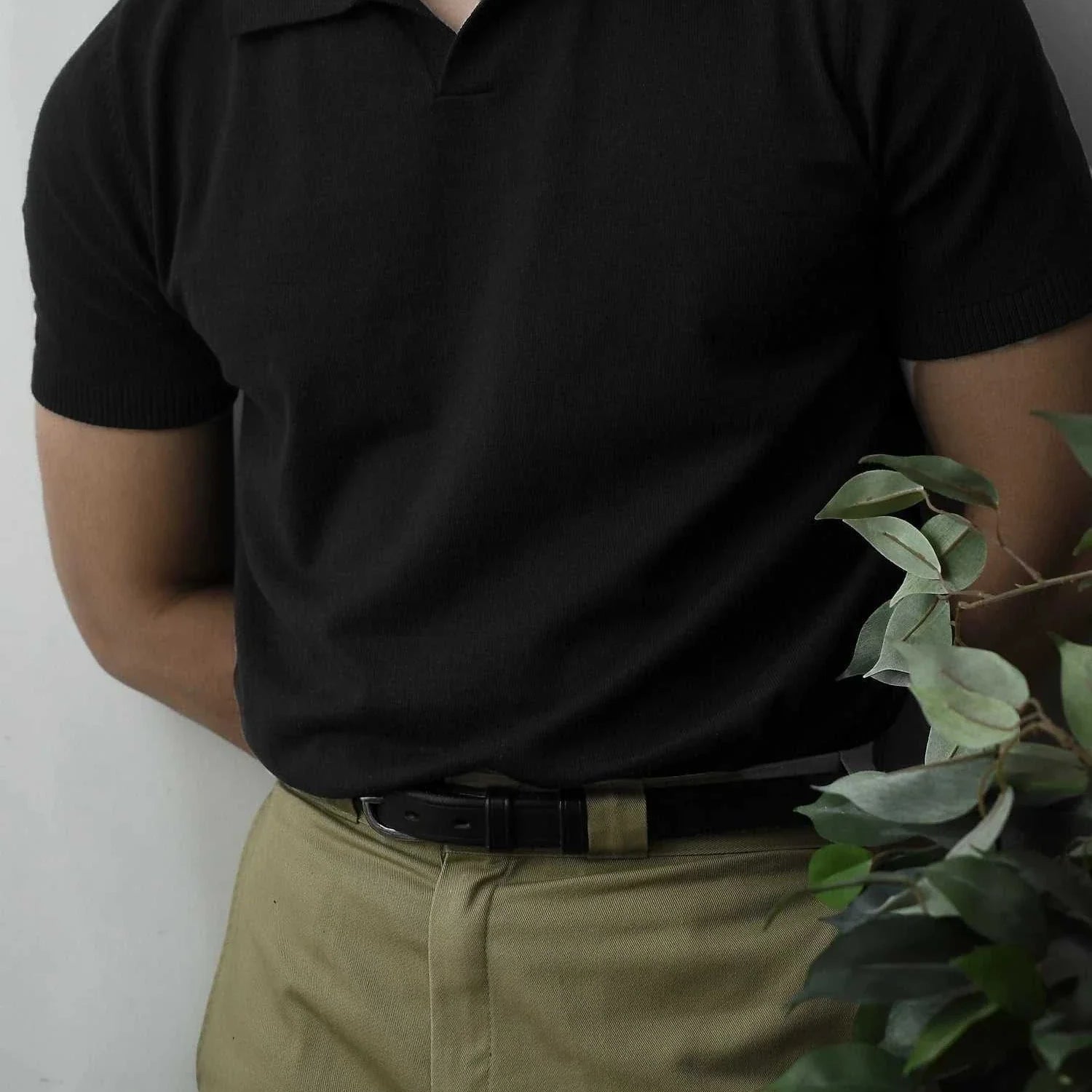 Man wearing black Old Money American polo t-shirt with khaki pants, showcasing casual elegance.