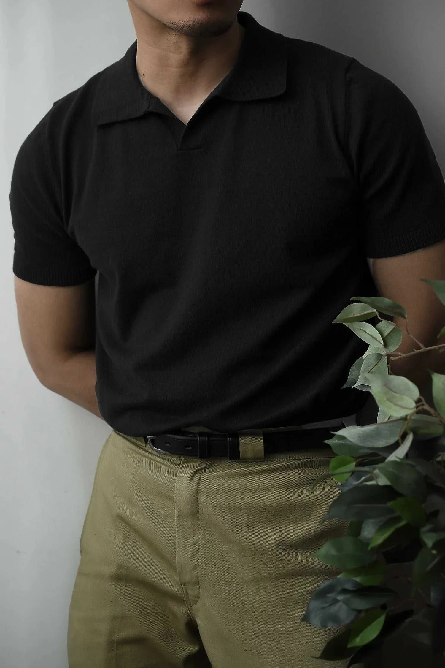 Man wearing black Old Money American polo t-shirt with khaki pants, showcasing casual elegance.