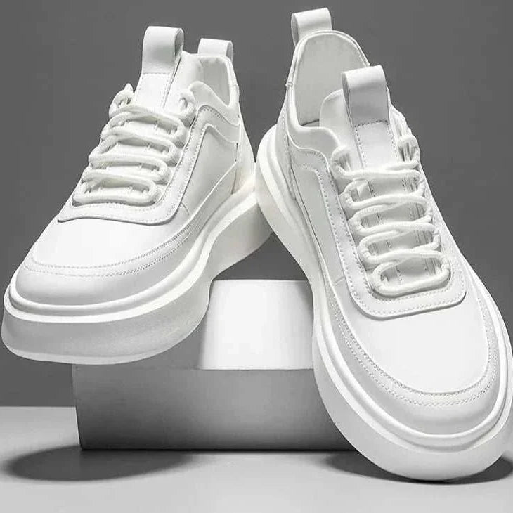 White basket comfort sneakers placed artistically, showcasing their contemporary design and breathable leather material for men.