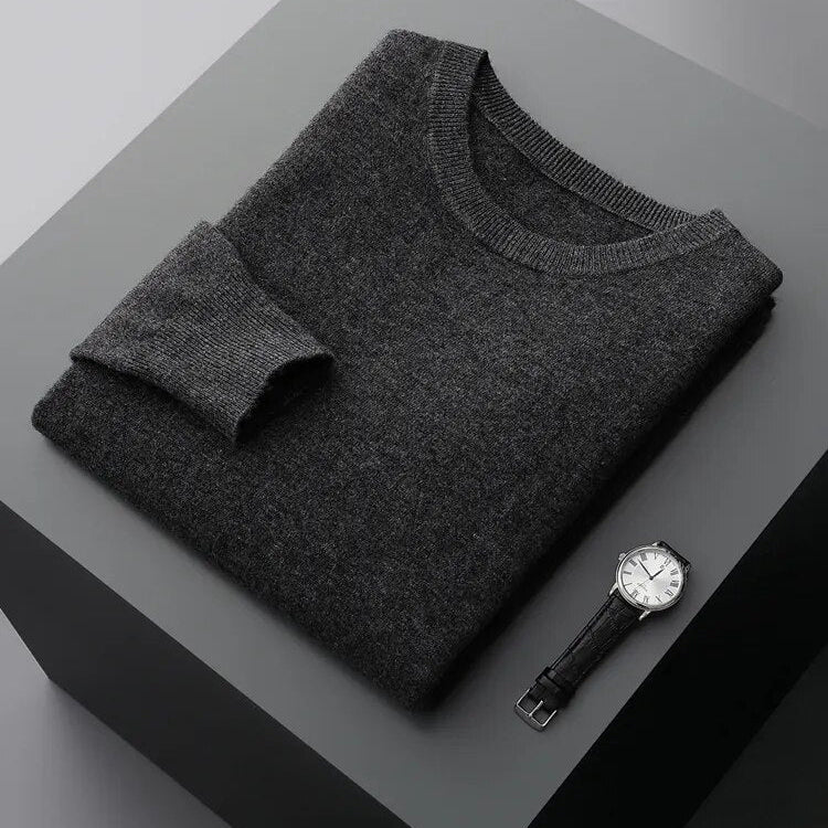 Antonios Pure Wool Sweater in dark grey folded on table with wristwatch nearby.