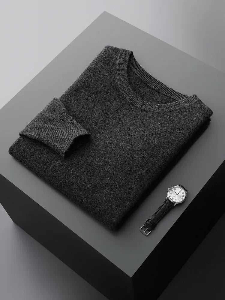 Antonios Pure Wool Sweater in dark grey folded on table with wristwatch nearby.