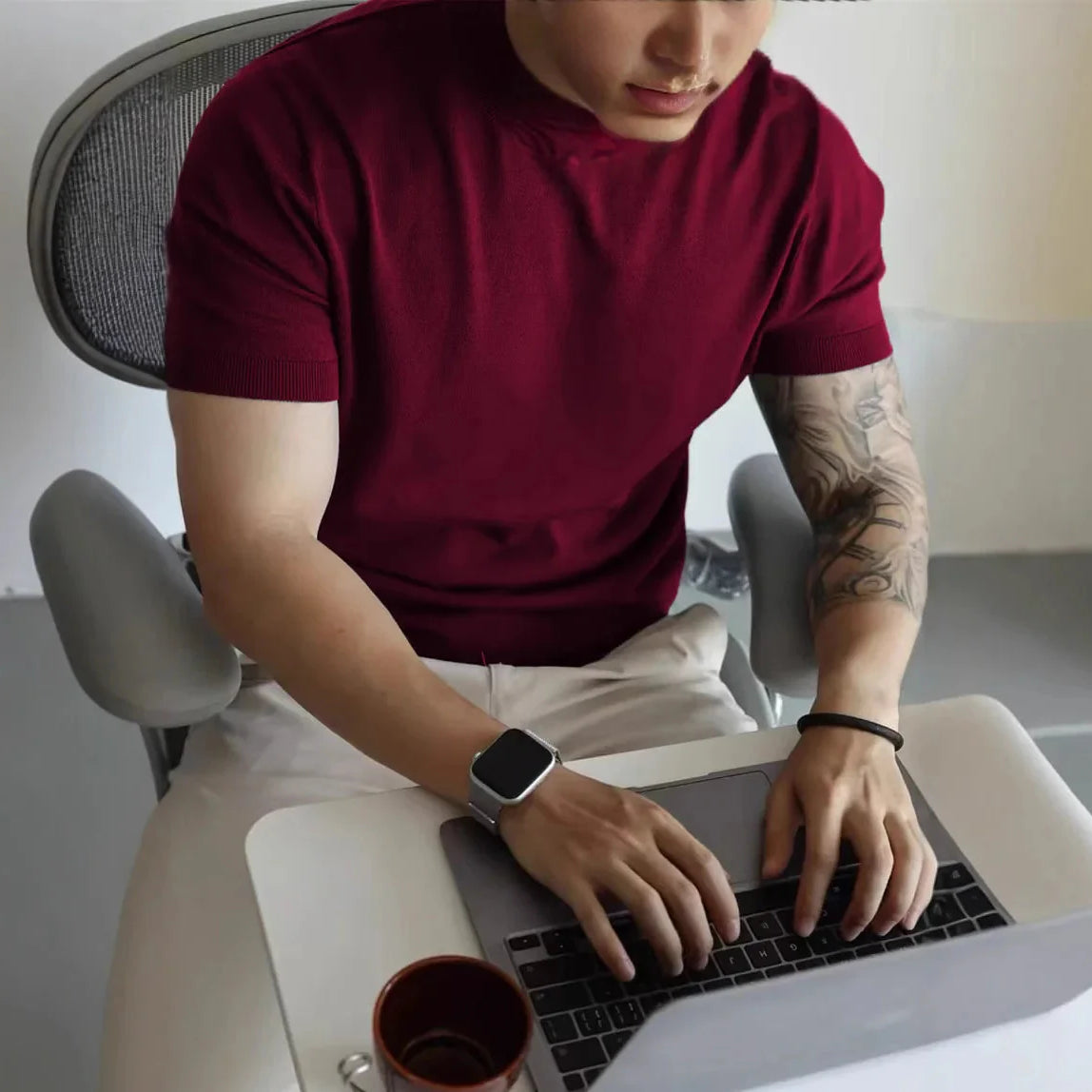 Male wearing a burgundy American cotton summer casual t-shirt while using a laptop.