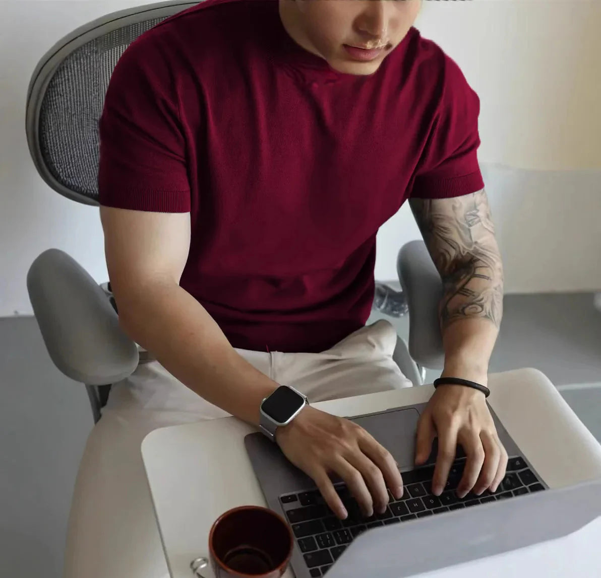 Male wearing a burgundy American cotton summer casual t-shirt while using a laptop.