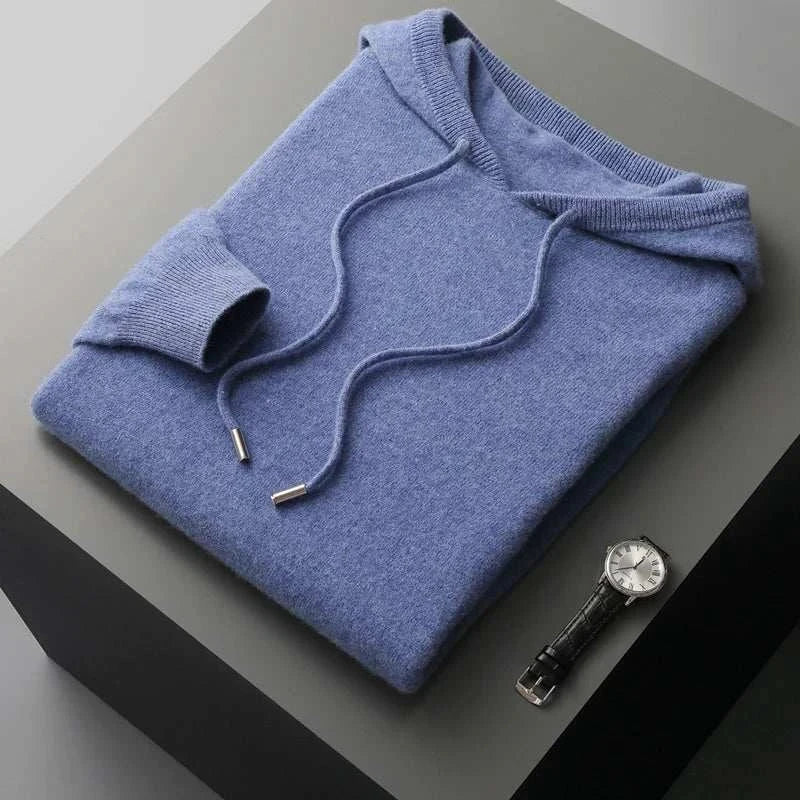 Blue wool cold season sweater for men, folded on a table with a watch.