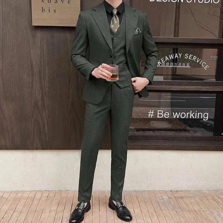 Groom wearing elegant 3 piece wedding suit with tie, holding a drink.