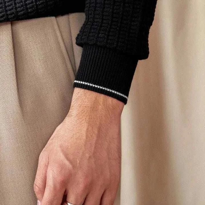 Close-up of a black winter wool sweater sleeve on a person.