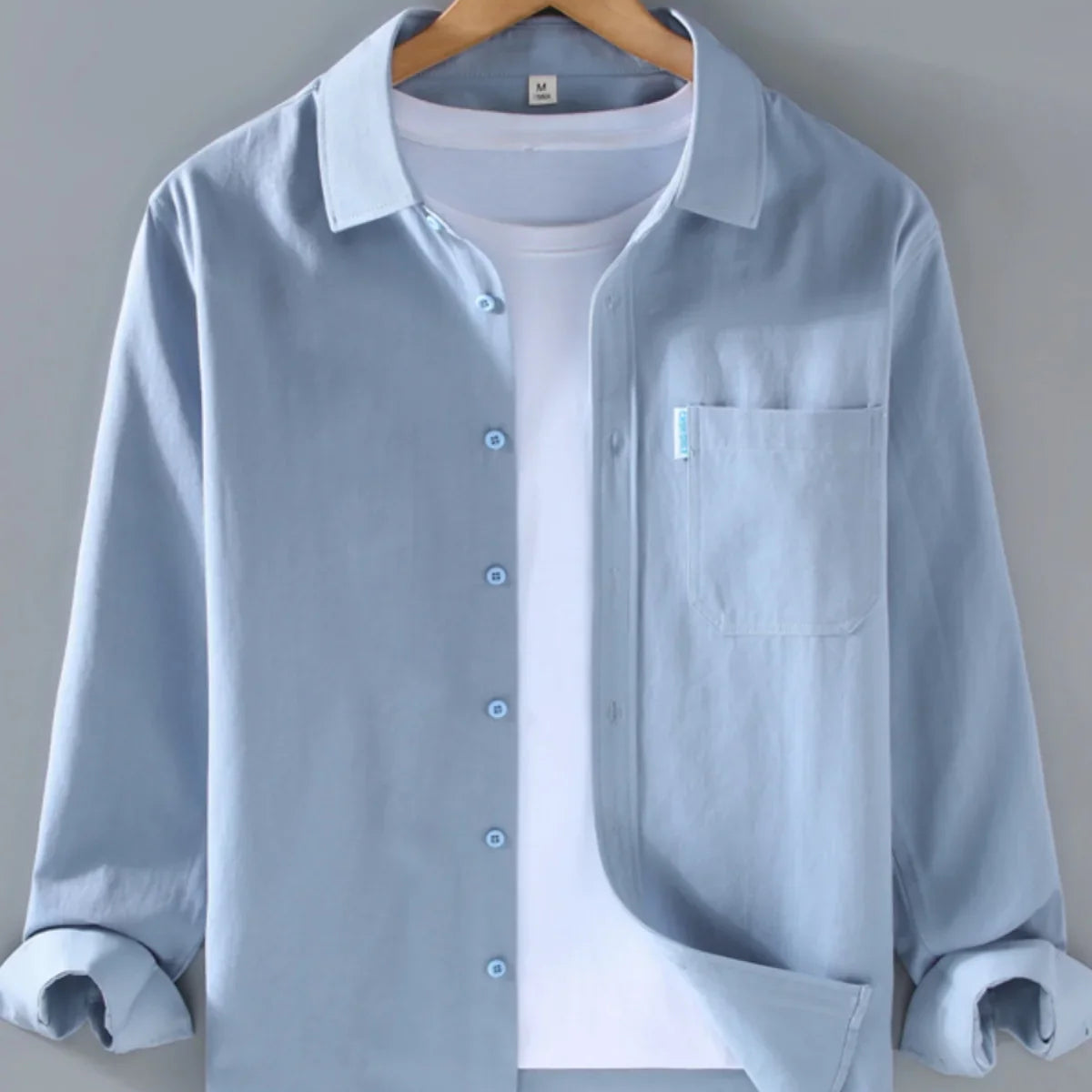 Spring solid color long sleeve button-up shirt hanging on a hanger.